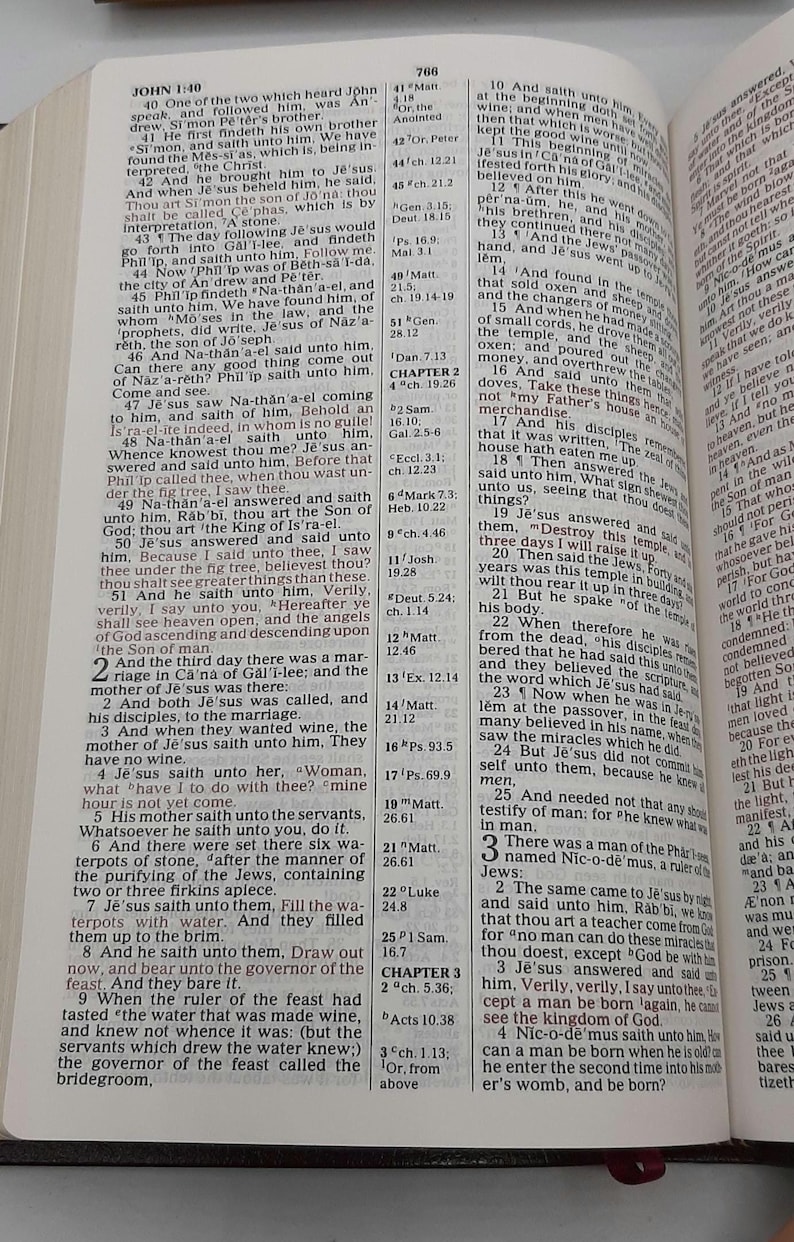May include: Open Bible with text from the Gospel of John, featuring chapter and verse notations. The pages are yellowed, and the text is in black. The book is open to a specific passage.