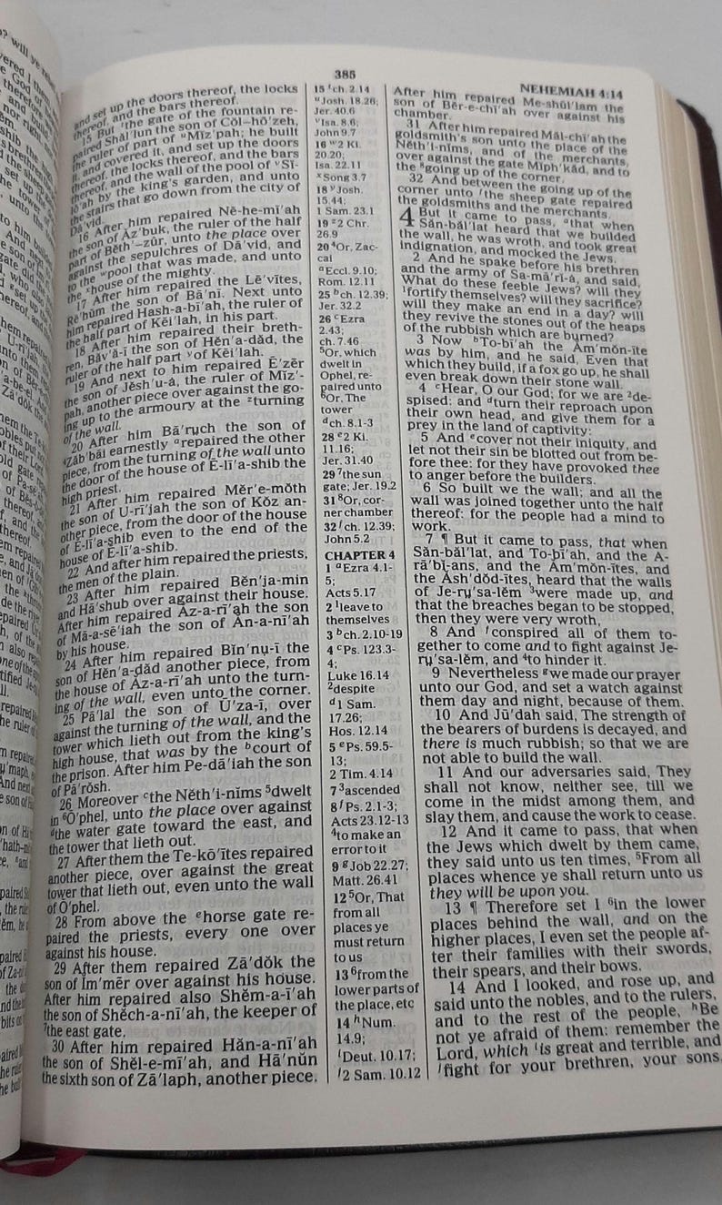 May include: An open book with text from the Bible, featuring the chapter title "Nehemiah 4:14" and a list of verses. The pages are yellowed, and the text is in black.