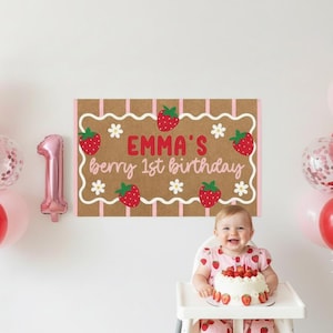 May include: A festive first birthday scene with a baby, balloons, and a cake. The backdrop features a sign that reads "Emma's berry 1st birthday." Balloons include strawberry and number one shapes, and pink and red spheres.