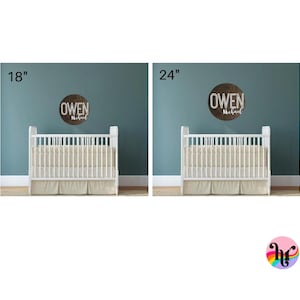 Puede incluir: Dos cunas blancas con ropa de cama beige, cada una con un letrero redondo de madera marr&oacute;n encima. El letrero de la izquierda dice "Owen Michael" y el letrero de la derecha dice "Owen Michael". El letrero de la izquierda tiene 18 pulgadas de di&aacute;metro y el letrero de la derecha tiene 24 pulgadas de di&aacute;metro.