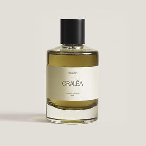 Könnte beinhalten: Eine klare Glasflasche mit ORÁLEA Haar- und Körperduft mit schwarzem Verschluss. Die Flasche enthält eine hell olivgrüne Flüssigkeit und hat ein weißes Etikett mit dem Markennamen und den Duftdetails. Die Flasche ist 100 ml.