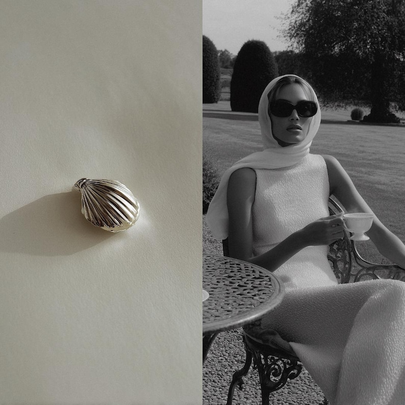 May include: A silver seashell-shaped pendant. The pendant has a ridged texture and is set against a white background. A person wearing sunglasses and a white dress is seated outdoors, holding a teacup.