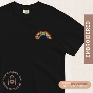 May include: Black t-shirt with a rainbow embroidered on the front. The text "LGBTO-WOMEN-AAPI OWNED SMALL BUSINESS" is printed in a circle on the bottom left of the shirt.
