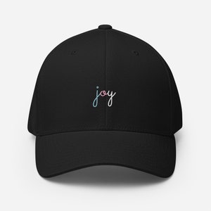 May include: Black baseball cap with a curved brim. The word "joy" is embroidered on the front in a cursive font, with a gradient of pink, blue, and white colors. The cap is made of a soft, durable material.