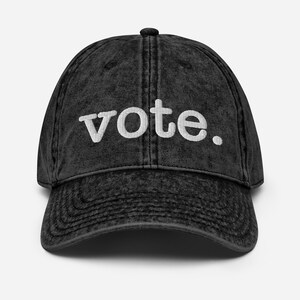 May include: A black vintage washed cotton baseball cap with white embroidered text that reads "vote."