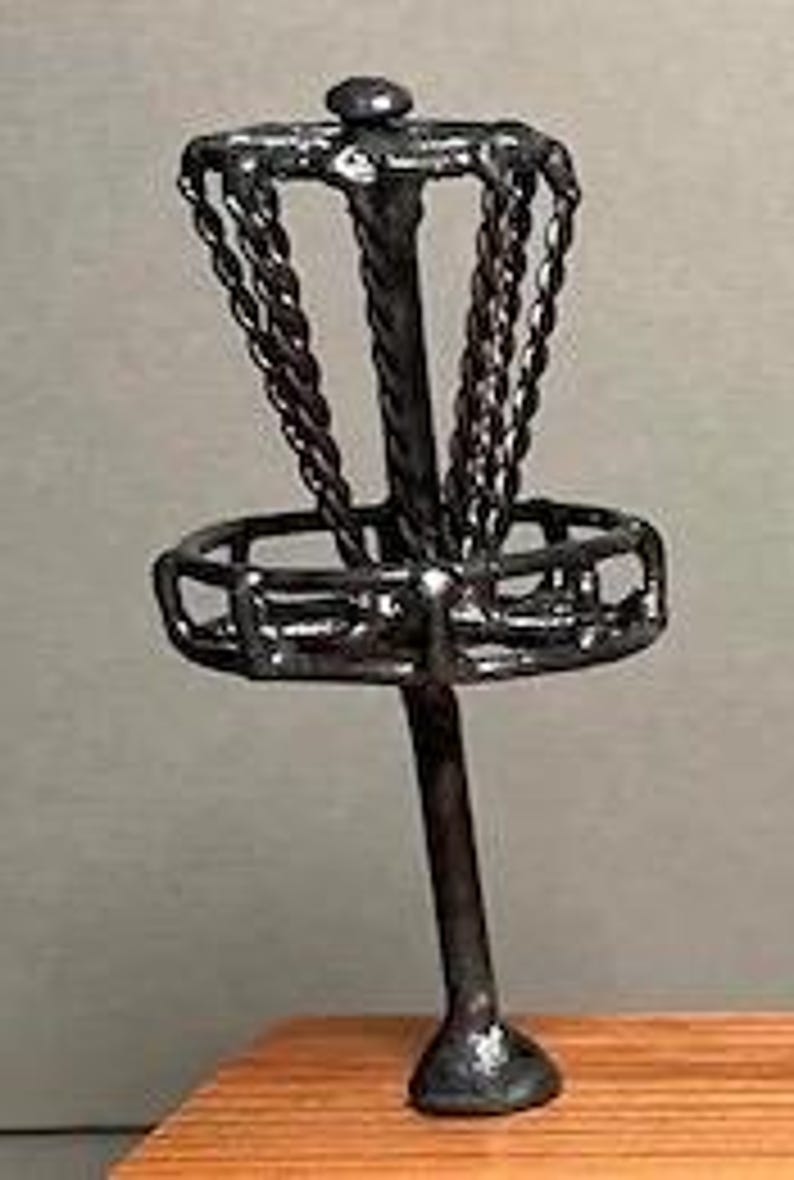 May include: A miniature black metal disc golf basket with a chain basket and a pole.
