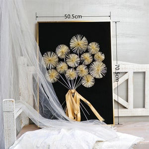 May include: Gold framed wall art featuring a bouquet of gold dandelion-like flowers on a black background. The artwork measures 50.5 cm wide and 70.5 cm high.