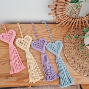 May include: Five handmade macrame heart ornaments with tassels in pink, yellow, purple, and blue.