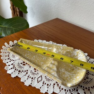 May include: A yellow ceramic dish with white speckles. The dish has three sections and is 8 inches long.