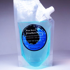 May include: A clear plastic pouch filled with blue liquid. The pouch has a label that reads "Blue Boost DinoNutrients Nutrient Enriched Seawater UV protection + anti-contamination GROW THE GLOW keep in a cool dark place PyroFarms.com".