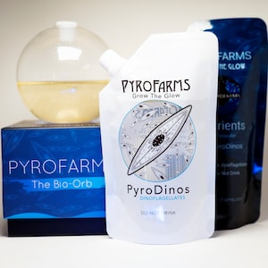 May include: A white pouch with the text "PYROFARMS Grow The Glow" and a microscopic image of a dinoflagellate. The pouch is labeled "PyroDinos DINOFLAGELLATES DO NOT DRINK".