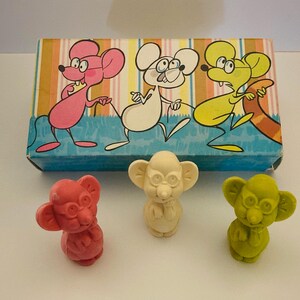 May include: A set of five eraser toppers shaped like mice. The mice are wearing glasses and have different colored bodies: pink, white, green, and yellow. The erasers are packaged in a box with a colorful cartoon design of mice.