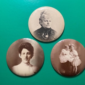 May include: Three vintage sepia-toned circular pins. The top pin features a portrait of a woman with a high-collared blouse. The bottom left pin shows a woman in a high-necked blouse. The bottom right pin depicts two children in dresses.