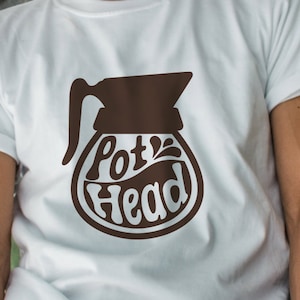 May include: White t-shirt with a brown graphic of a coffee pot and the text "Pot Head".