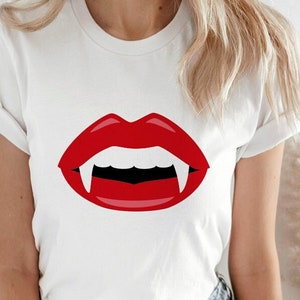 May include: White t-shirt with a red vampire mouth graphic featuring fangs.