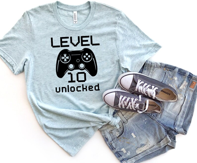May include: A light blue t-shirt with a black graphic of a video game controller and the text "LEVEL 10 unlocked".