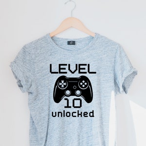 May include: Gray t-shirt with a black video game controller graphic and the text "LEVEL 10 UNLOCKED".