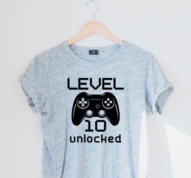 May include: Gray t-shirt with a black video game controller graphic and the text "LEVEL 10 UNLOCKED".