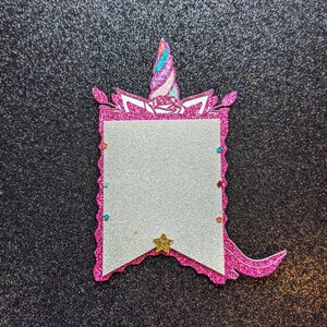 May include: Pink glitter unicorn banner with a white space for writing. The banner has a gold star and a pink glitter tail.
