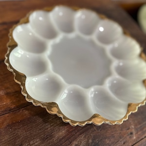 Peut inclure: Plat à œufs en céramique blanche avec un bord doré et une bordure festonnée. La plaque comporte six compartiments individuels pour contenir des œufs.