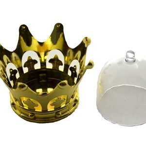 Puede incluir: Un portavelas dorado en forma de corona con una tapa transparente en forma de c&uacute;pula. La corona tiene un dise&ntilde;o decorativo con formas recortadas. La tapa tiene un peque&ntilde;o asa en la parte superior. Art&iacute;culos para la decoraci&oacute;n del hogar.