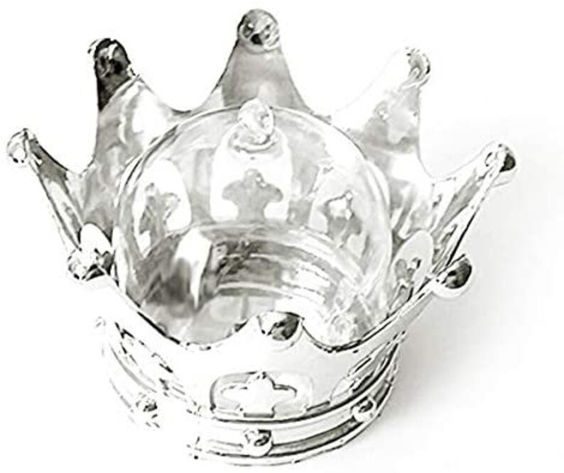 Puede incluir: Un recipiente plateado en forma de corona con una c&uacute;pula de cristal transparente. La corona tiene tres puntas prominentes y detalles decorativos. La c&uacute;pula de cristal se asienta en la base de la corona, creando una presentaci&oacute;n &uacute;nica.
