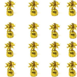 May include: A grid of twenty-one individually wrapped gold foil candies. Each candy has a rounded base and is topped with a decorative gold foil bow. The candies are arranged against a white background.