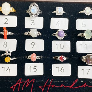 May include: A display of 18 rings with various gemstones and settings. The rings are arranged in a grid pattern on a black background. The numbers 1 through 18 are printed below each ring.