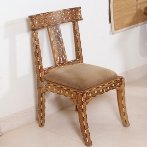 May include: A wooden chair with intricate inlaid designs in a light wood and dark wood pattern. The chair has a brown fabric seat and a simple, straight back.
