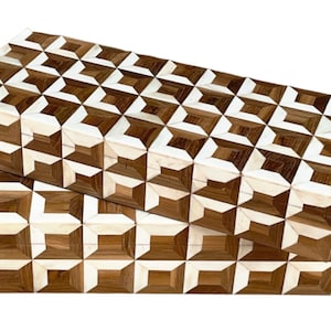 Puede incluir: Dos cajas decorativas con un patrón geométrico de madera y hueso. Las cajas están apiladas una encima de la otra. El patrón es un diseño repetitivo de cuadrados y triángulos.