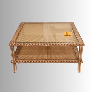 Pode incluir: Uma mesa de centro quadrada com tampo de vidro e prateleira inferior, ambas com superf&iacute;cies de palhinha tran&ccedil;ada. A estrutura de madeira &eacute; decorada com intrincados padr&otilde;es florais brancos incrustados. Uma etiqueta amarela com o texto LEELAWATI ARTS &eacute; vis&iacute;vel.