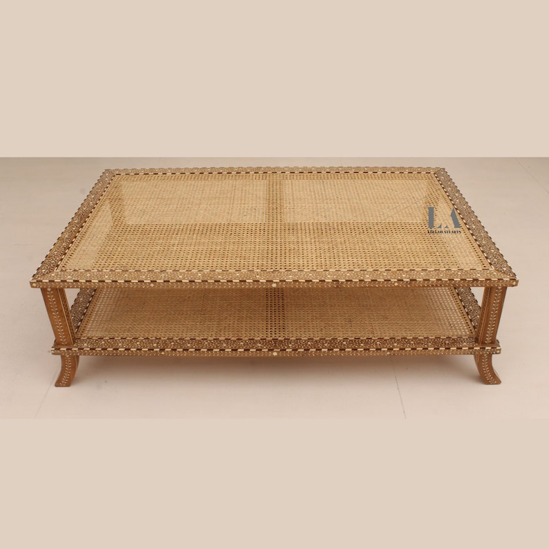 Pode incluir: Uma mesa de centro retangular com tampo de palhinha natural e prateleira inferior. A estrutura de madeira &eacute; decorada com padr&otilde;es incrustados complexos ao longo das bordas e apoiada por quatro pernas curvas. O texto LA LILA ARTS &eacute; vis&iacute;vel.