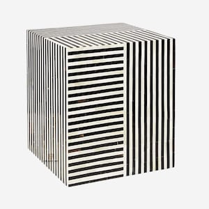 May include: A black and white striped cube-shaped stool made of bone inlay. The stool has a geometric pattern of stripes.