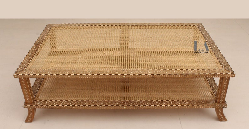 Pode incluir: Uma mesa de centro retangular com tampo e prateleira inferior em palhinha tran&ccedil;ada. A estrutura de madeira &eacute; decorada com padr&otilde;es intrincados de incrusta&ccedil;&otilde;es brancas. O texto LA LALATE ARTS &eacute; vis&iacute;vel no topo. A mesa tem quatro pernas curvas.