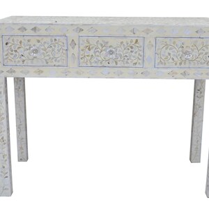 May include: A white console table with three drawers, decorated with floral and leaf patterns. The mosaic-style design covers the top, drawers, and legs. The table is approximately 100 cm in length.