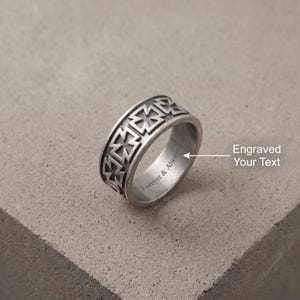 Könnte beinhalten: Ein silberfarbener Metallring mit einem sich wiederholenden geprägten Kreuzmuster auf dem äußeren Band. Die Innenseite des Rings ist mit dem Text Forever & Always graviert, dazu ein Pfeil zur Gravur und der Text Engraved Your Text.