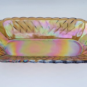 May include: A vintage iridescent glass serving dish with a woven pattern. The dish is oval shaped and has a light brown colour with a rainbow sheen.