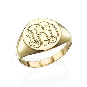 May include: A gold signet ring with a round, engraved top featuring a monogram. The ring is a classic style and would make a great gift.