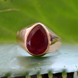 Op de afbeelding: Een ring met een peervormige robijn-edelsteen gezet in een gouden band.