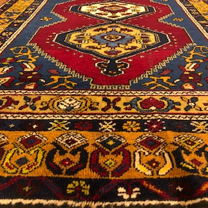 Könnte beinhalten: Ein traditioneller persischer Teppich in Rot, Blau und Gold. Der Teppich zeigt komplizierte florale und geometrische Muster.