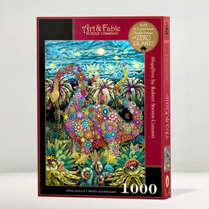 Op de afbeelding: Een doos van 1000 stukjes puzzel van Art & Fable Puzzle Company. De puzzel toont een kleurrijke illustratie van een bloemenwezen in een tuin. De doos heeft de tekst "Megaflora by Robert Steven Connett" en "Soft & Luxurious Puzzle Pieces with ZERO GLARE!"