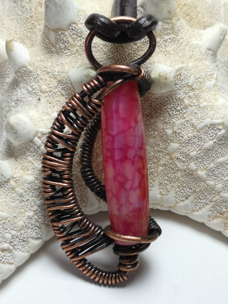 A small pendant made with copper wire woven and wrapped around a dragon vein agate bead..reversible