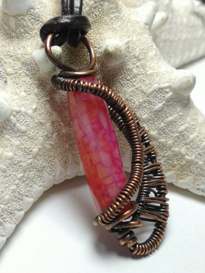 A small pendant made with copper wire woven and wrapped around a dragon vein agate bead..reversible