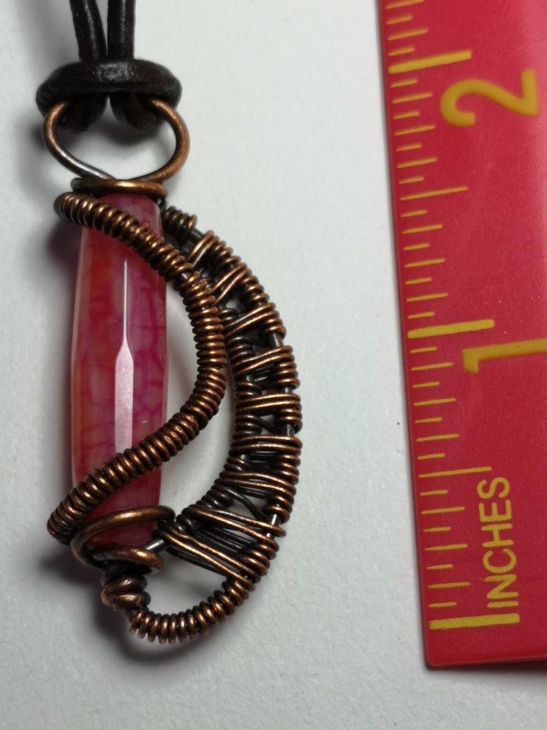 A small pendant made with copper wire woven and wrapped around a dragon vein agate bead..reversible