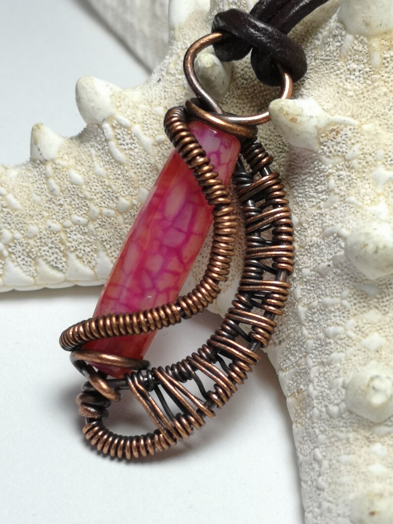 A small pendant made with copper wire woven and wrapped around a dragon vein agate bead..reversible