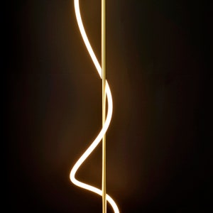 May include: A gold floor lamp with a curved, white LED light source. The lamp has a wooden base.