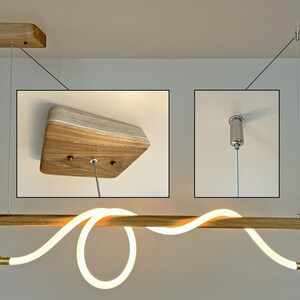 May include: A modern wooden light fitting with a curved LED light strip. The light is suspended from the ceiling by a thin cable and has a wooden canopy.