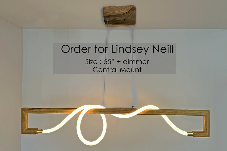 May include: A modern, wooden light fixture with a white, curved LED light. The fixture is 55 inches long and has a central mount. The text "Order for Lindsey Neill" and "Size: 55" + dimmer Central Mount" is visible in the image.