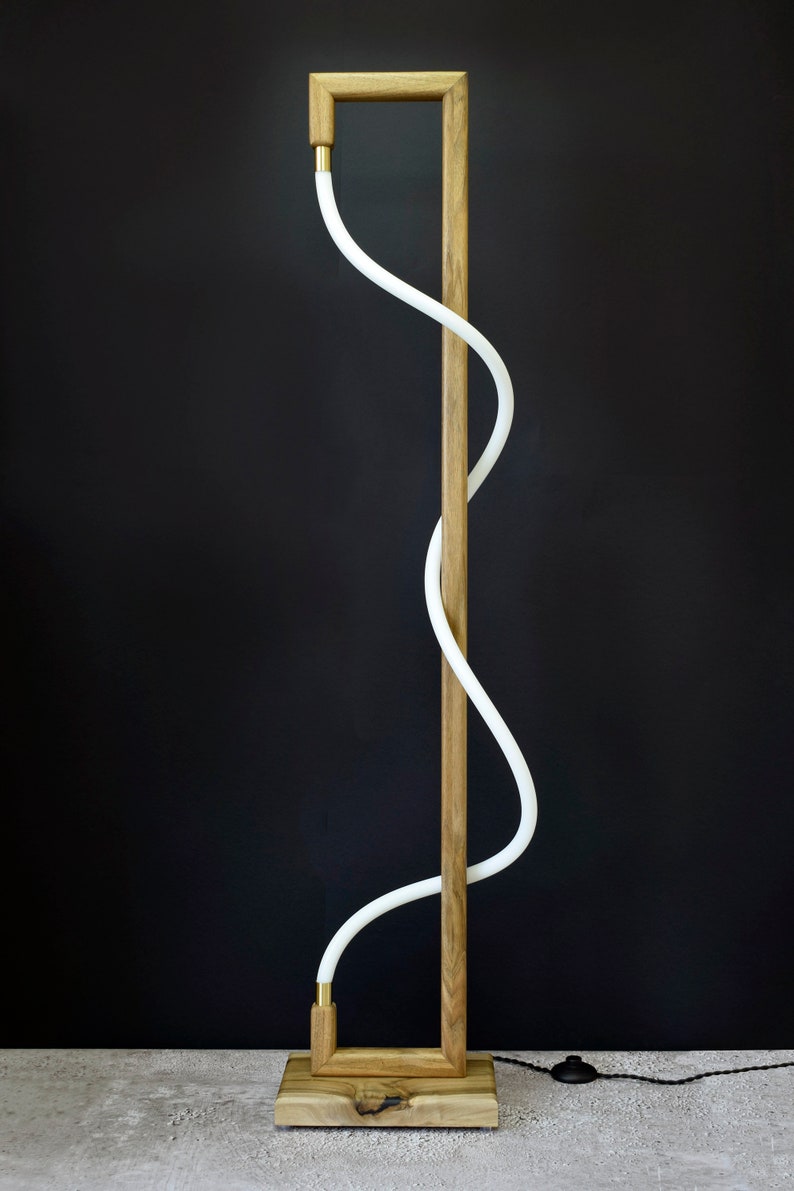 Pu&ograve; includere: Una lampada da terra moderna con un'illuminazione bianca curva e una struttura in legno. La lampada ha un design semplice e minimalista e sarebbe un'ottima aggiunta a qualsiasi casa moderna.