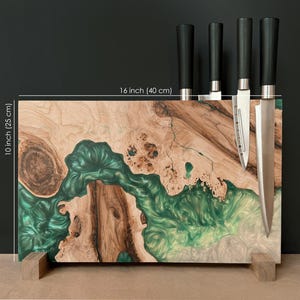 May include: A wooden knife block with a green and white epoxy resin design, measuring 16 inches (40 cm) wide and 10 inches (25 cm) tall. It features a magnetic knife holder with four knives with black handles.